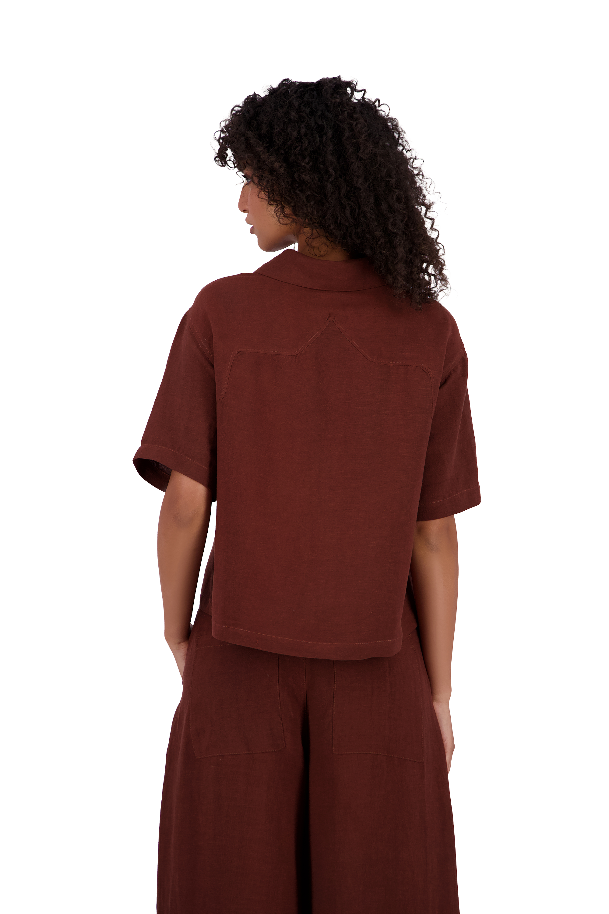 A model shown from the back wearing a rust-brown short-sleeve collared shirt and matching wide-leg pants against a solid white background. #Burnt_Clove