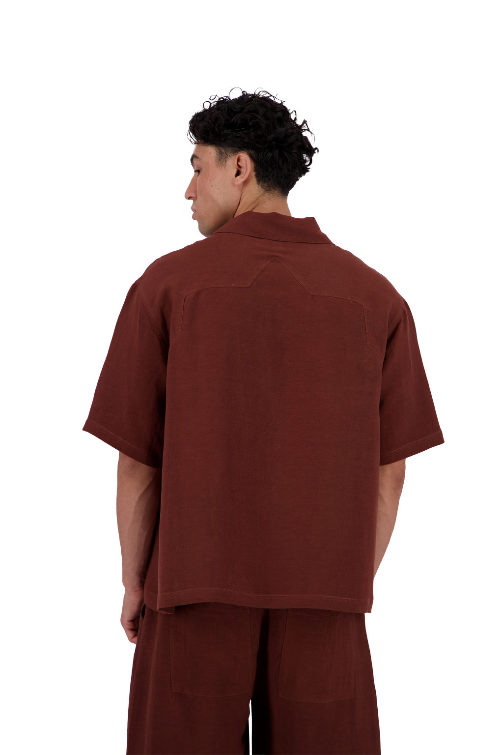 A man shown from the back wearing a rust-brown short-sleeve collared shirt and matching brown pants against a plain white background. #Burnt_Clove