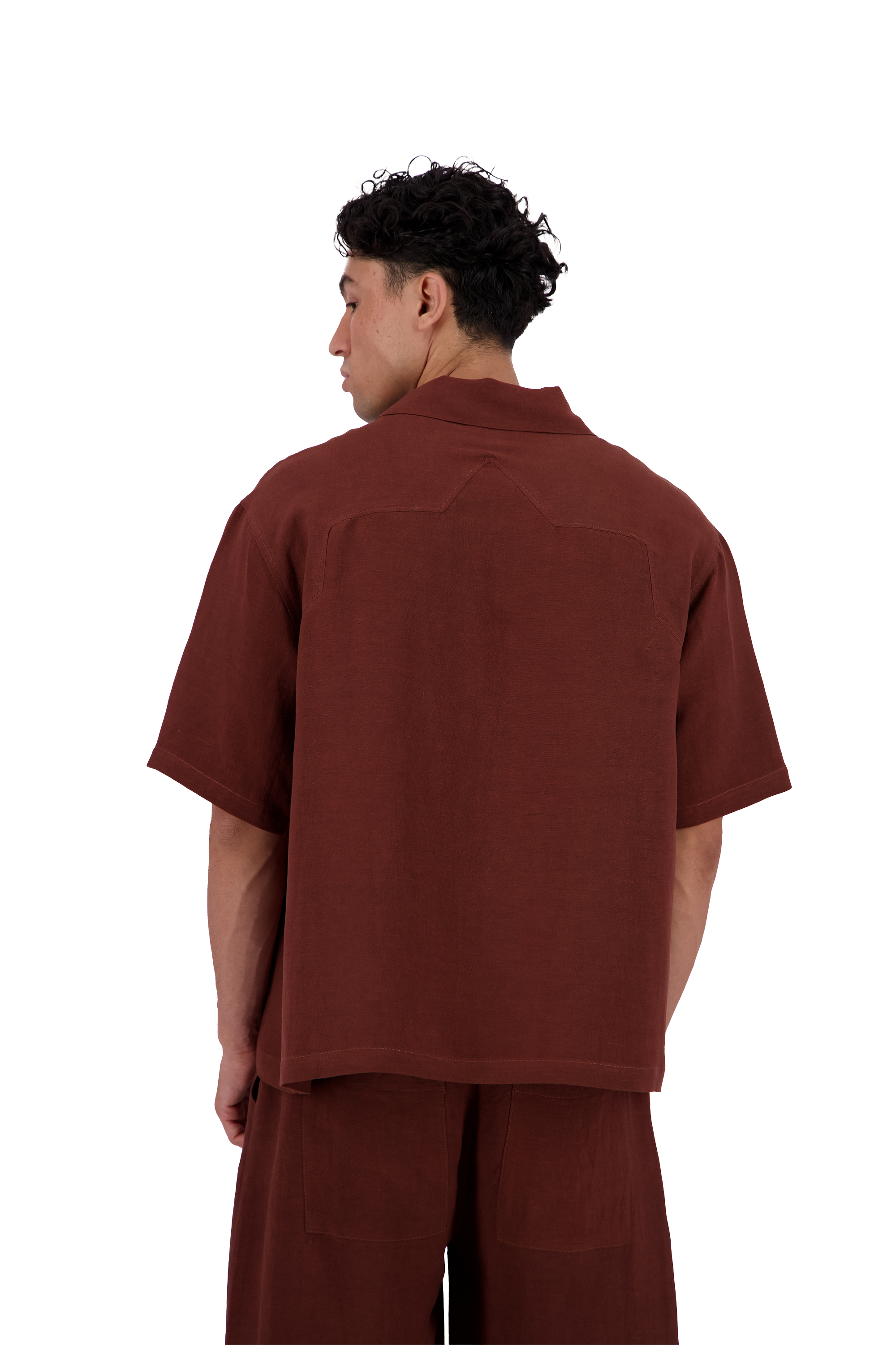 A man shown from the back wearing a rust-brown short-sleeve collared shirt and matching brown pants against a plain white background. #Burnt_Clove