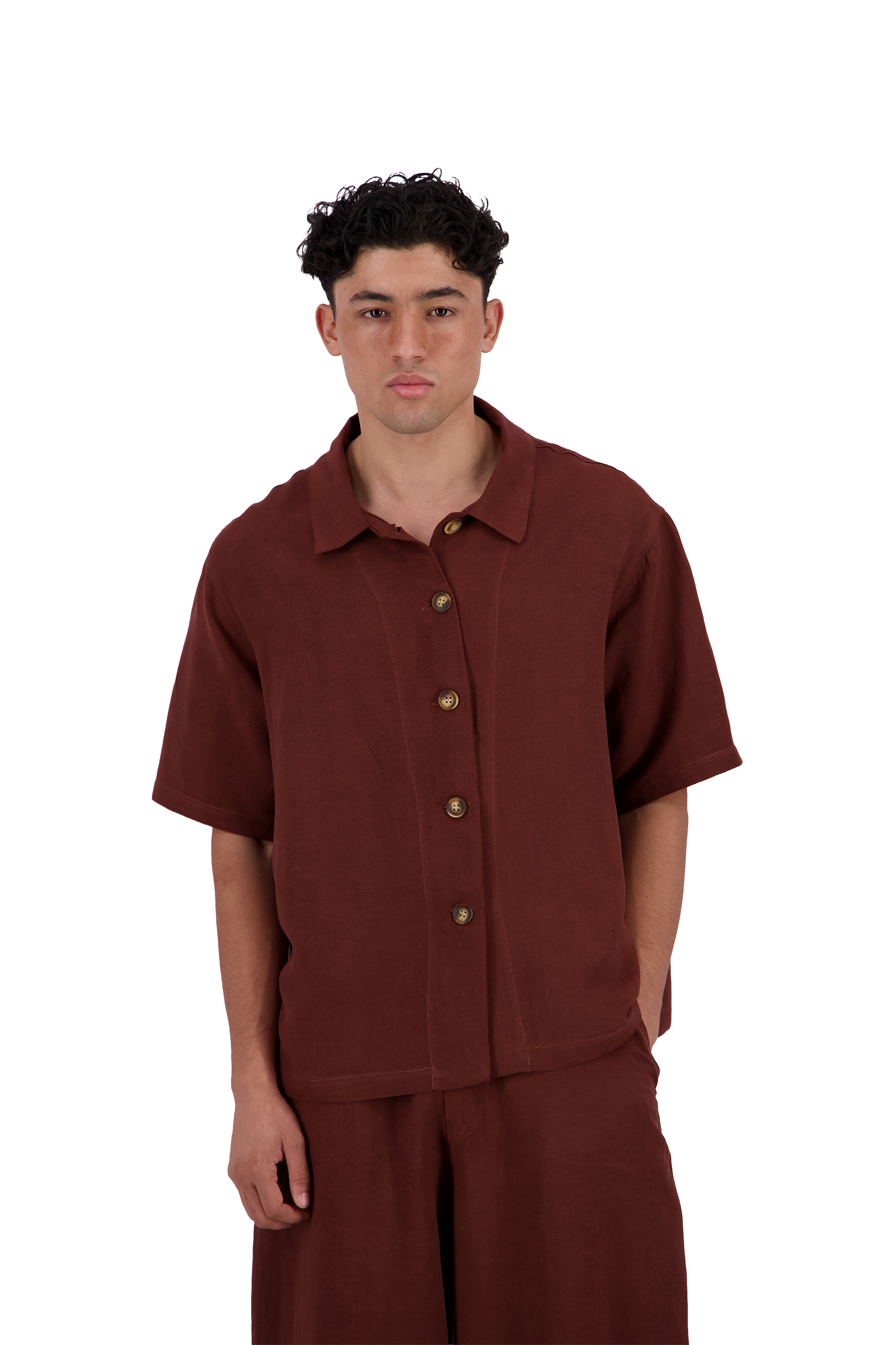 A man wearing a rust-brown short-sleeve button-up shirt and matching pants, standing against a plain white background. #Burnt_Clove