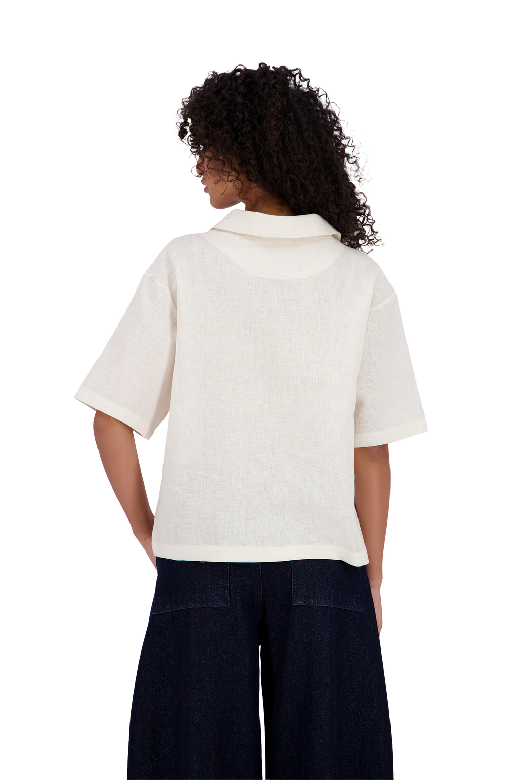 A woman viewed from the back wearing a short-sleeve cream-colored collared shirt and dark navy wide-leg pants, set against a plain white background. #Milk_Dune