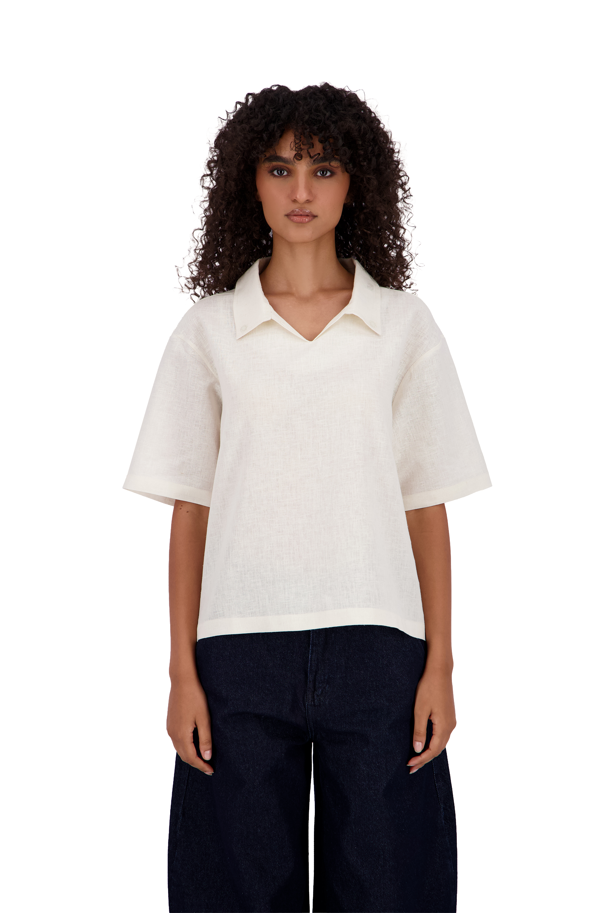 A model with curly dark hair wearing a short-sleeve, collared knit top in off-white and dark navy pants, shot against a solid white background. #Milk_Dune