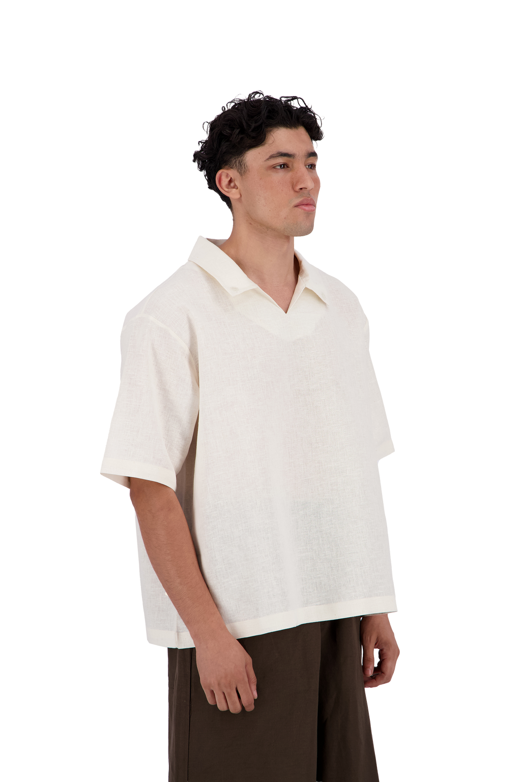 A man wearing a short-sleeve, v-neck knit polo shirt in off-white, paired with dark brown trousers, photographed against a solid white background. #Milk_Dune